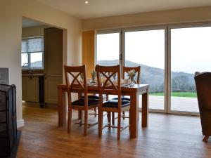 uma sala de jantar com mesa, cadeiras e janelas em Bluebell Lodge em Llandrindod Wells