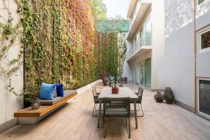een patio met een tafel en stoelen en een groene muur bij Capitalia San Angel Inn in Mexico-Stad