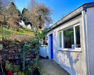 a house with a blue door and a stone wall at Crag End Farm Retreat, Rogerscale, Nr Cockermouth in Lorton