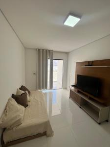 Habitación blanca con cama y TV de pantalla plana. en APTO NOVO TODO MOBILIADO A 400 M DA PRAIA Sensacional, en Porto Seguro