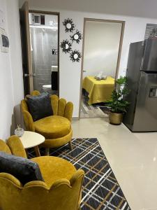 a living room with yellow chairs and a table and a bed at Lindo Apartaestudio cerca al centro in Itagüí