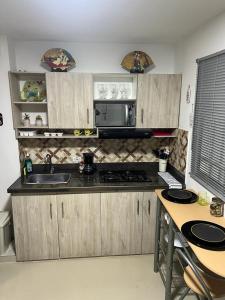 cocina con armarios de madera, fregadero y microondas en Lindo Apartaestudio cerca al centro en Itagüí