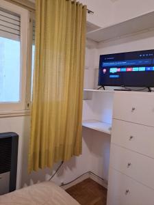 1 dormitorio con TV y cortina amarilla en Nidito de amor Monoambiente en Mar del Plata