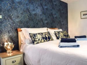 a bedroom with a white bed with a blue wall at Leofric Lodge in Bampton