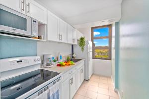 a kitchen with white cabinets and a sink and a window at Aloha Hawaii, Waikiki Condo with Great Mountain Views & Free Parking! in Honolulu