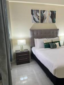 a bedroom with a bed and a table with a lamp at Odyssey Exquisite @ Charlemont in Kingston