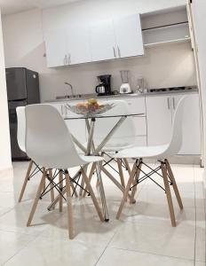 cocina con mesa y 2 sillas blancas en Acogedor Apartaestudio, en Pitalito