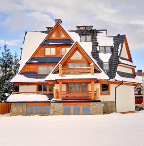 a house with snow on top of it at Willa Misiaga Apartamenty in Murzasichle