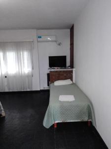 um pequeno quarto com uma cama e uma televisão em Complejo Semaso em Santa Rosa