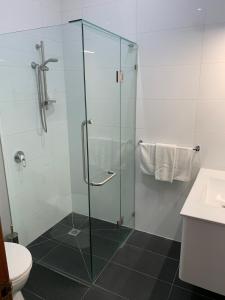 y baño con ducha de cristal y aseo. en Miner's Retreat Motel en Ballarat