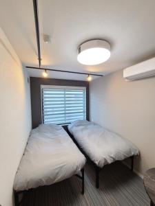 a small room with two beds and a window at パーリーフラッツ品川高輪台 PEARLY FLATS Shinagawa Takanawadai in Tokyo