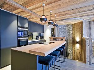 a kitchen with a large wooden counter with stools at Appartement de Luxe avec SPA et Terrasse - 8 Couchages, Méribel - FR-1-613-44 in Méribel