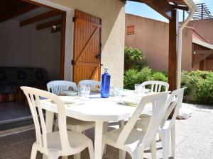 - une table blanche avec des chaises blanches et une bouteille bleue dans l'établissement Maison Gruissan, 2 pièces, 6 personnes - FR-1-229-839, à Gruissan