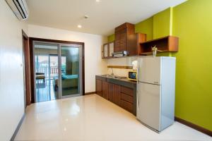 a kitchen with a white refrigerator and green walls at Lanta Garden Hill Resort and Apartment in Ko Lanta