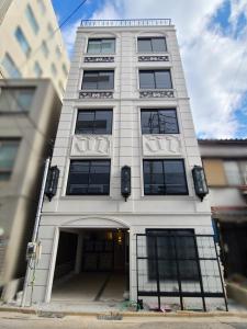 a tall white building with an entry way at パーリーフラッツ品川高輪台 PEARLY FLATS Shinagawa Takanawadai in Tokyo