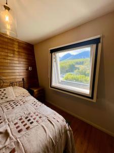 1 dormitorio con ventana grande y cama grande en Departamento New Vintage con hermosas vistas a las montañas y al Canal en Ushuaia