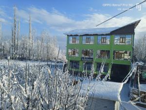 zielony dom na śnieżnym polu z drzewami w obiekcie Hotel Gulmarg Residency, Kunzer Gulmarg w mieście Gulmarg
