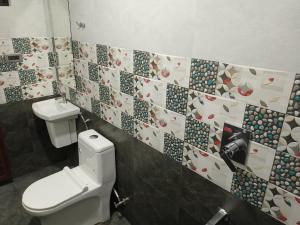 uma casa de banho com um WC e uma parede de azulejos em La casa de Alexa homestay em Idukki