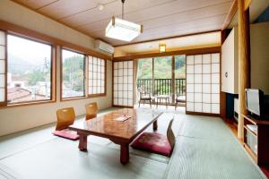 una sala da pranzo con tavolo, sedie e finestre di Ayameya Ryokan a Nakanojo