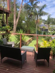 a deck with chairs and a table and trees at Water Street - Garden Views in Forster