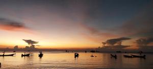 een zonsondergang op een strand met boten in het water bij Ava 2 Budget Hotel Koh Tao in Ko Tao
