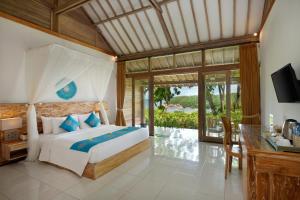 Schlafzimmer mit einem Bett, einem Schreibtisch und einem TV in der Unterkunft The Acala Shri Sedana in Nusa Lembongan