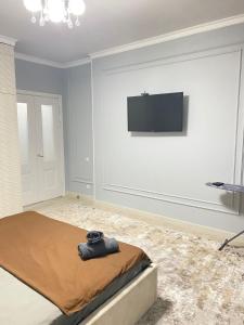 a bedroom with a bed and a flat screen tv on the wall at Люкс квартира в центре города Шымкент in Shymkent