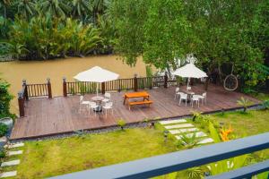 a wooden deck with tables and chairs and umbrellas at Kampot Tropical Village in Kampot