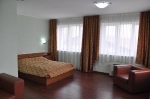 a bedroom with a bed and a chair and windows at Dvorik Hotel in Krasnoyarsk