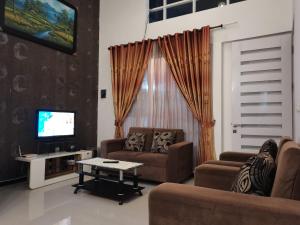a living room with two couches and a tv at Villa Asri in Batu