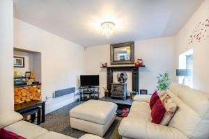 a living room with a white couch and a fireplace at Bwthyn Y Nant in Dinorwic