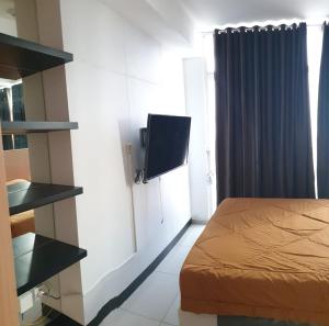 a bedroom with a bed and a tv on a wall at Troom treepark city apartement in Kebun Nanas