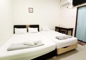 1 dormitorio con 2 camas con sábanas blancas en MN Ferringhi Inn en Batu Ferringhi
