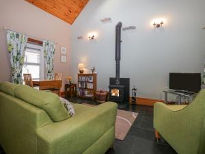 a living room with a green couch and a fireplace at Thimble Cottage in Ulverston