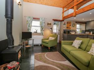 sala de estar con sofá verde y fogones en Thimble Cottage, en Ulverston