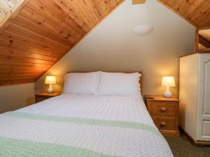 1 dormitorio con 1 cama blanca y 2 lámparas en Thimble Cottage, en Ulverston