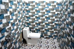 a bathroom with a toilet and a mosaic wall at Rani Homestay Khajuraho in Khajurāho