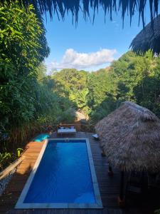 una piscina con sombrilla de paja y un complejo en Le 19 des Hauts Manguiers, en Nosy Be