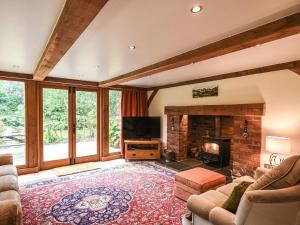 a living room with a fireplace and a tv at Keepers Cottage in Picklescott