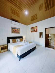 a bedroom with a large bed and a wooden ceiling at The Banana House in Nusa Penida