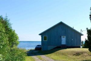 a blue barn with a car parked next to the water at **WATERFRONT**BEAUTIFUL MODERN TOBERMORY COTTAGE in Miller Lake