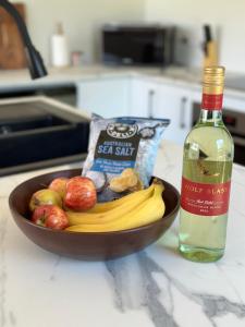 a bowl of fruit and a bottle of wine on a counter at Luxury Holiday Unit 8min walk to Town Center with Boat Parking in Mallacoota