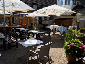 eine Terrasse mit Tischen und Sonnenschirmen in einem Restaurant in der Unterkunft Hotel Bienefeld in Korschenbroich