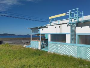 Suo Oshima的住宿－イマジンウエストオーシャン（ImagineWestOcean），田野边的蓝色和白色建筑