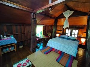 a bedroom with a bed in a room with wooden walls at Khoom Kam Kaew in Phrao