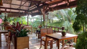 a restaurant with wooden tables and chairs and plants at Kep Lodge in Kep
