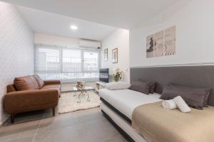 1 dormitorio con 2 camas, silla y sofá en Dobohomes - Clara del Rey 33, en Madrid