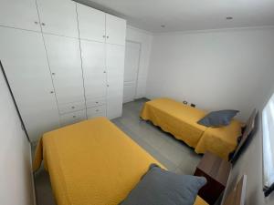 1 dormitorio con 2 camas, armarios blancos y sábanas amarillas en Casa condominio costa del Sol a 1.4 km de Bahía Inglesa en Caldera
