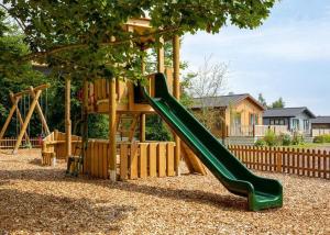 a playground with a green slide in a yard at Otters Mead Boutique Lodges in Beetley