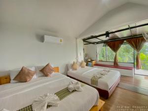 2 Betten in einem Zimmer mit Fenster in der Unterkunft The Owl Khaokho in Khao Kho